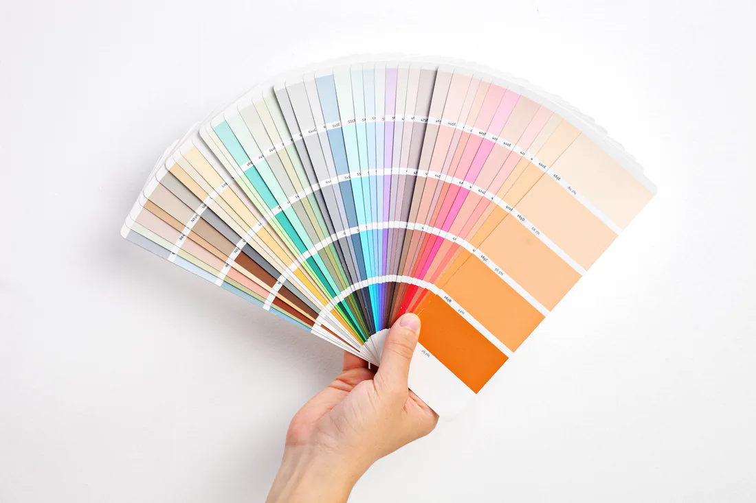 Hand holding an open fan of paint colour samples