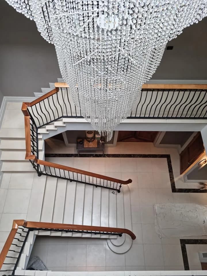 Sweeping staircase and landing beneath a crystal chandelier, freshly painted