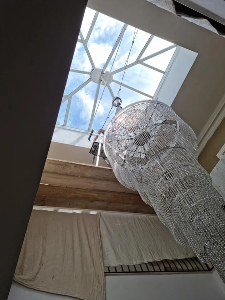 Chandelier being fitted below a roof lantern during a decorating project