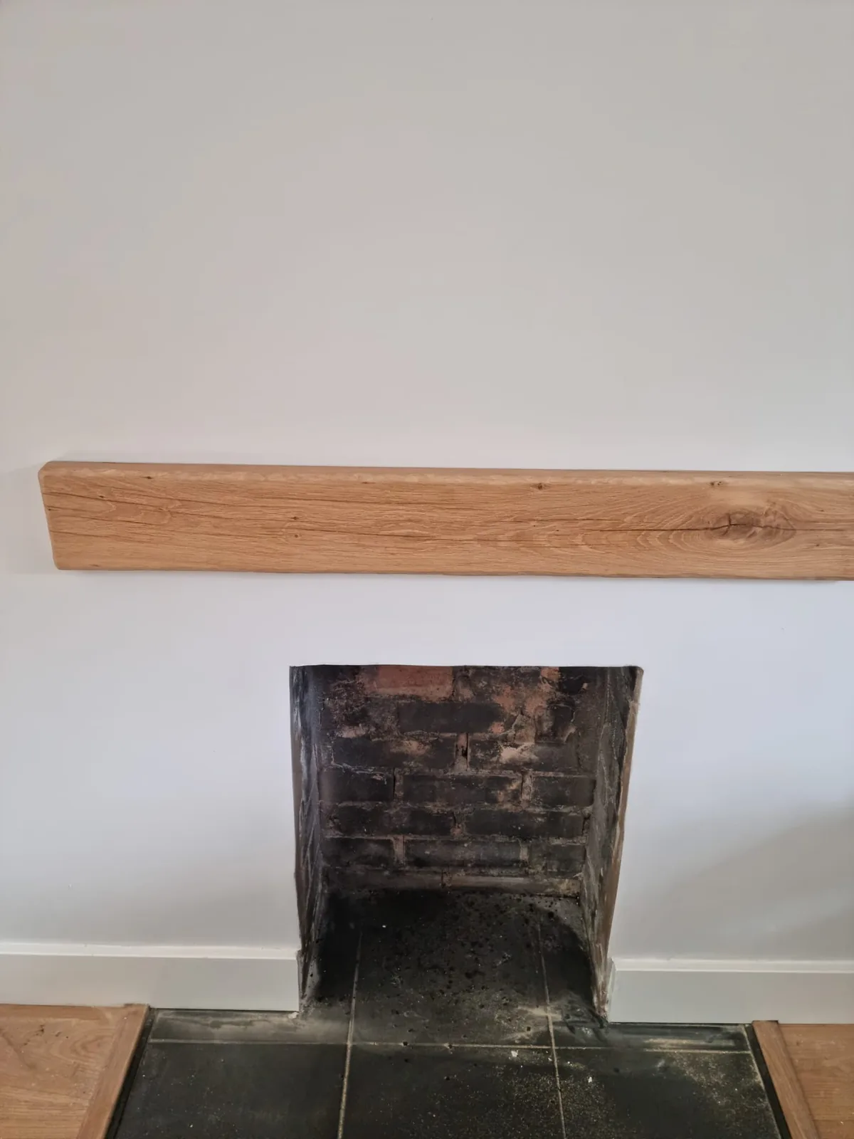 Reclaimed oak mantel beam fitted above an opened fireplace