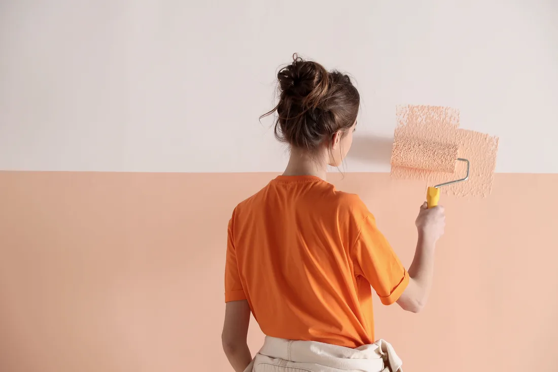 Decorator rolling a soft terracotta colour onto a wall