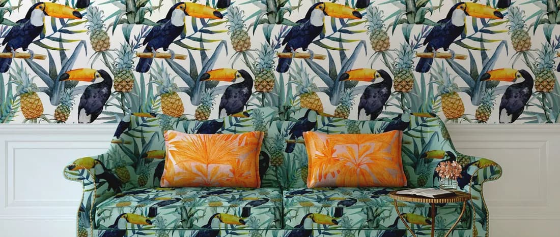 Tropical patterned wallpaper behind a patterned sofa